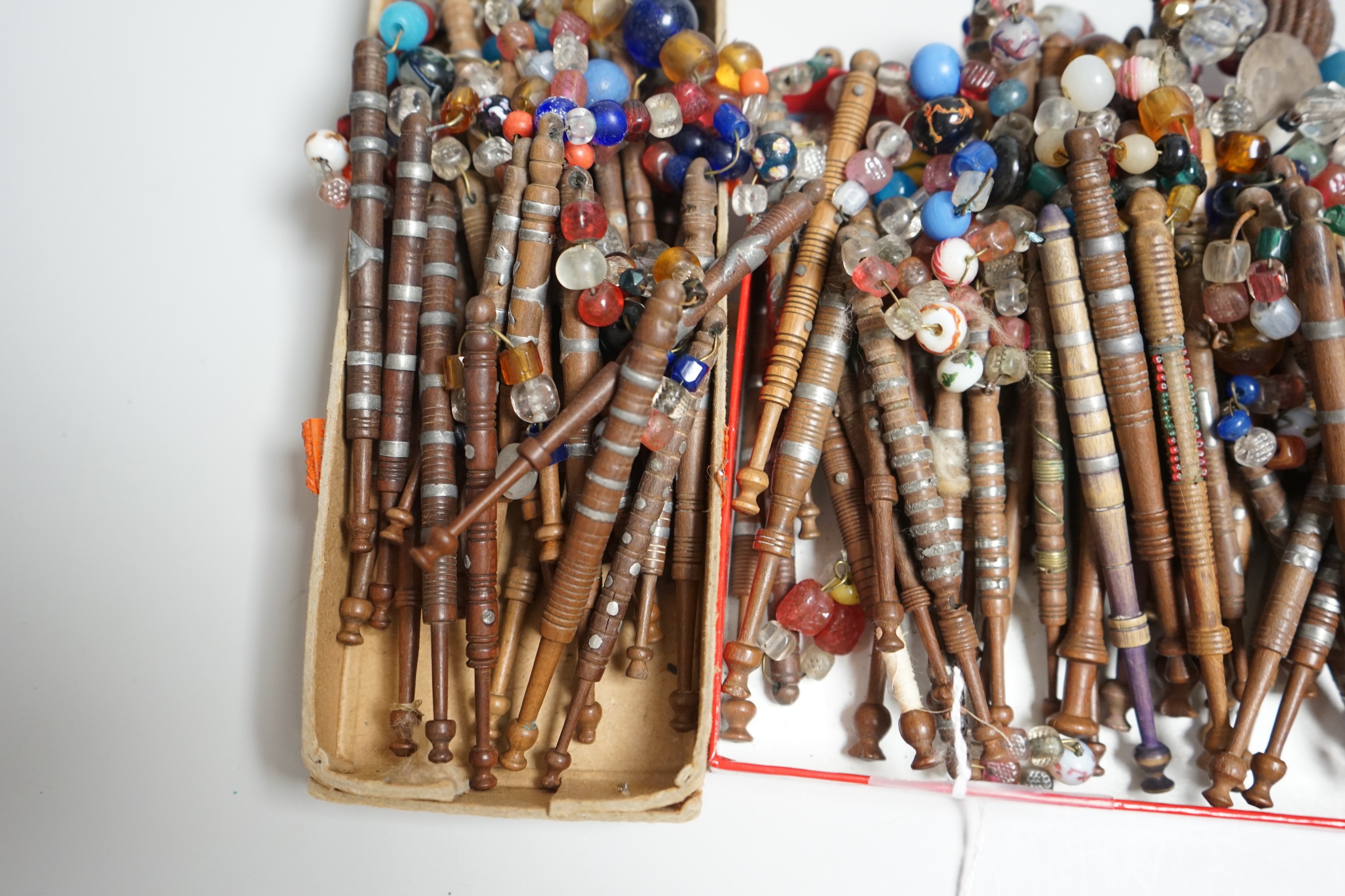 Eighty 19th century wood and metal decorated lace bobbins with coloured beaded tops